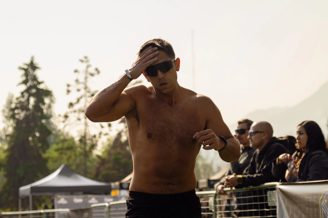 A contraluz, un atleta con gafas de sol se seca el sudor de la frente durante Hybrid Monkey V5, junto al público que sigue la carrera.